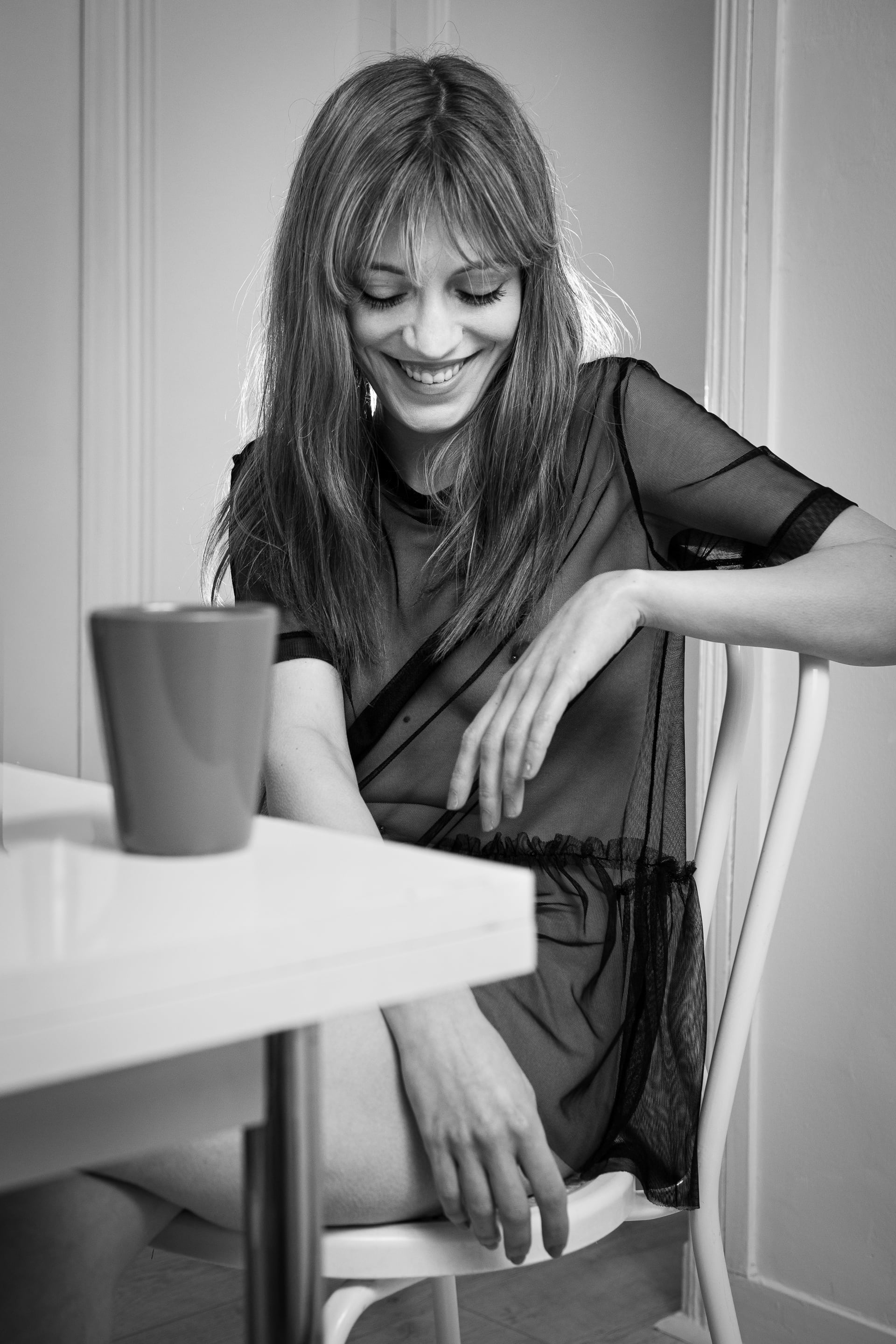 Femme élégante au sourire naturel lors d une séance photo boudoir glamour en intérieur.