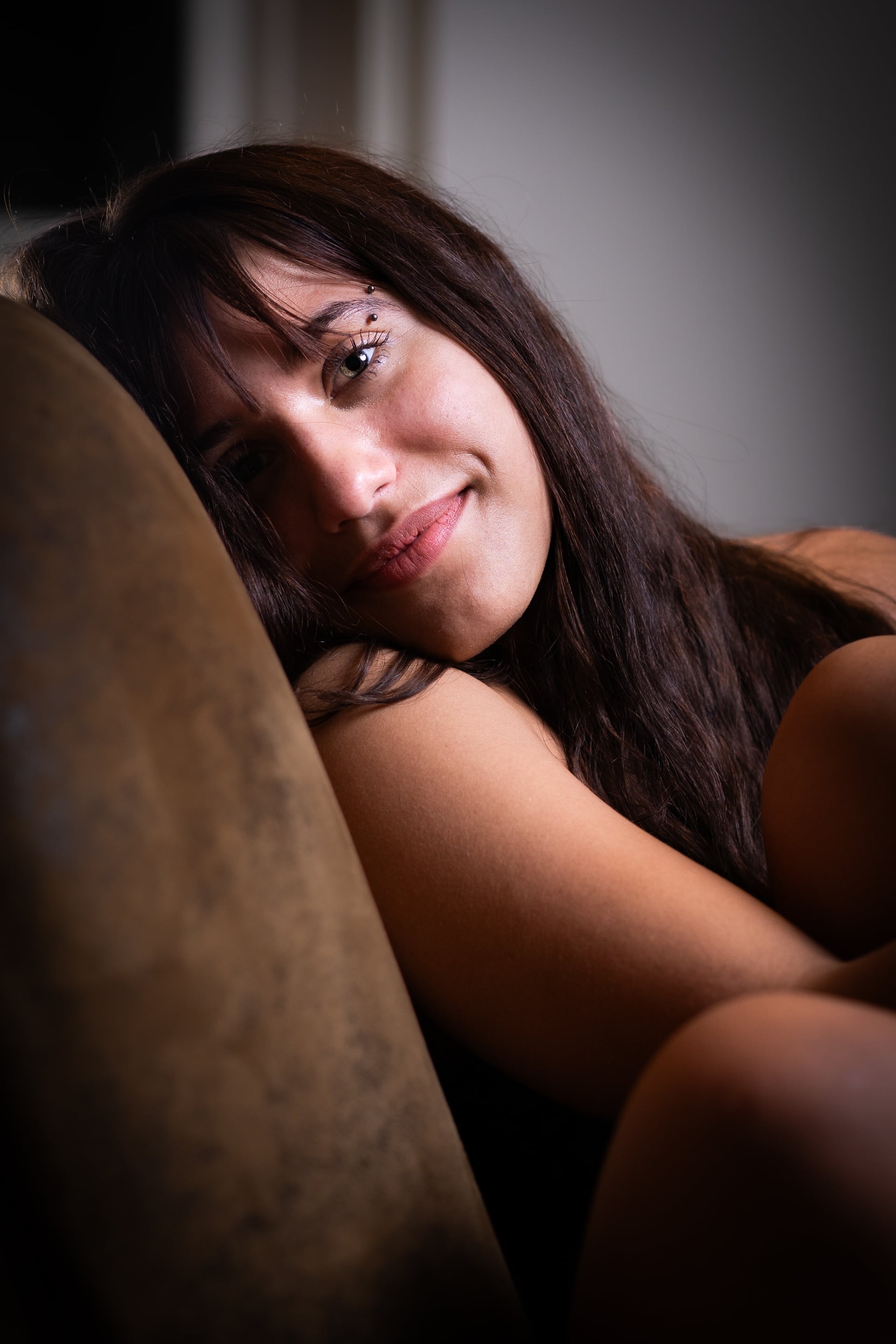 Woman with a soft gaze and natural smile during an elegant boudoir photo session indoors.